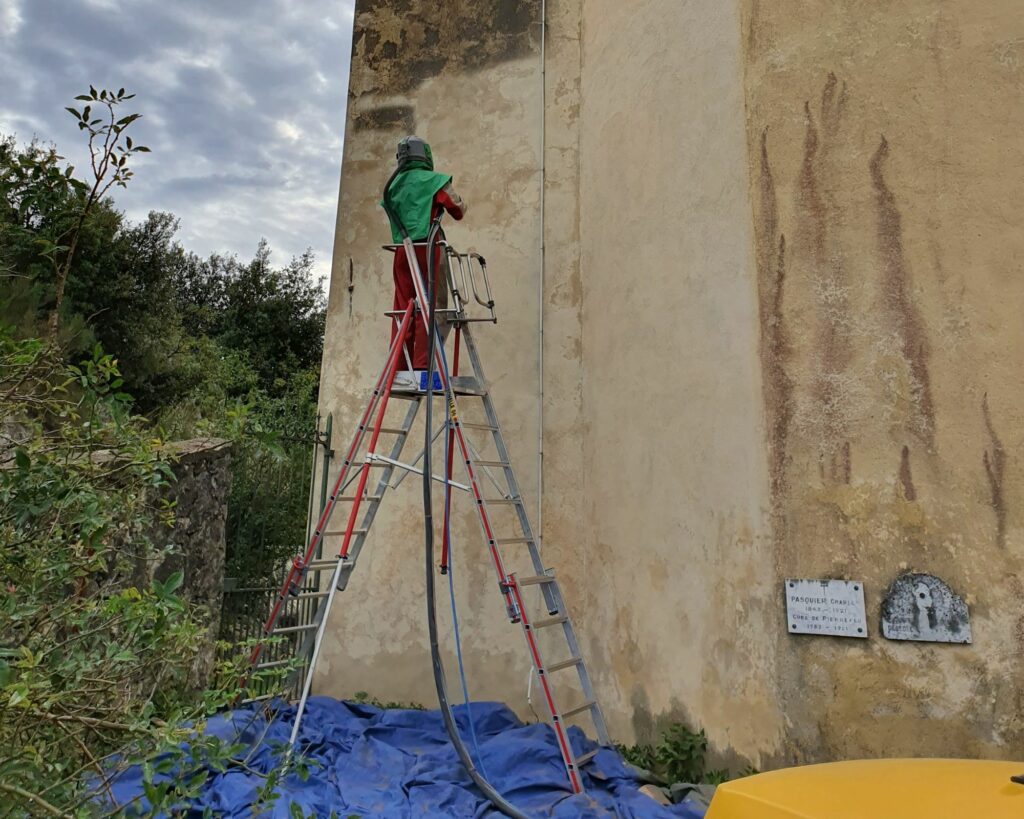 Homme utilisant la technique de l'aérogommage sur une façade